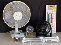 Photo showing all items in the lot including the Super Fan, smaller Honeywell Fan, Lumilite flashlight with stand, Lynk organizer in packaging, over-the-door racks, and dimmer switch.