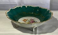 Footed porcelain bowl showing scalloped green interior with gold gilding and central hand-painted roses bouquet.