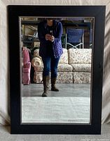 Full front view of large black framed mirror showing reflection and overall condition