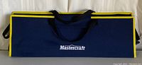 Closed navy blue and yellow Mastercraft carrying case with handles.