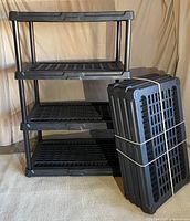 Full view of one fully assembled shelving unit with three open grid shelves and one bundle of unassembled shelving parts including shelves and legs/posts.