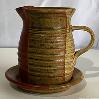 Photo of pitcher jug showing vertical ribbing and two-tone brown and tan glaze with handle and pouring spout