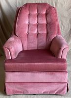 Front view of the pink velour swivel rocker chair showing tufted backrest, padded arms, and seat cushion.