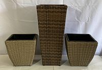 Front view of two small square planters and one tall rectangular planter showing woven wicker-like texture and plastic liners