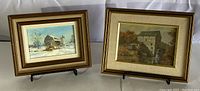 Two framed artworks side-by-side, showing a snowy barn winter scene and an autumn mill print.