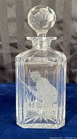 Front view of clear crystal decanter with etched fisherman holding fishing rod.