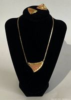 View of black display bust showing the full necklace and the pair of clip-on earrings set next to the necklace top area.