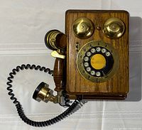 Front view of the vintage wooden wall telephone showing the full unit with handset and coiled cord.