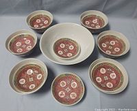 View from above of the decorated bowls arranged around one larger plain white bowl, showing the red patterned bowls with Chinese characters and borders.