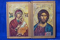 Two wooden plaques side by side, showing Virgin Mary holding baby Jesus and Jesus Christ with a book, both with halo and angels, mounted in wooden frame.