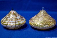 Two iridescent blown art glass oil lamps with web-like gold and white patterns on a dark blue backdrop from front angle.