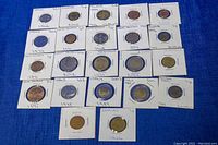 Top view of 22 assorted collectible coins mounted in holders showing labels with country and years (Great Britain, Spain, Italy, Poland) and various denominations.