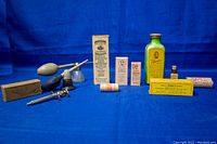 Photo showing full lot with various antique medical tools and vintage bottles with printed labels on a blue cloth background.