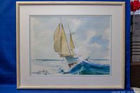 Framed watercolour painting showing a sailboat with tan sails on ocean waves, signed by Harry John Johnson.