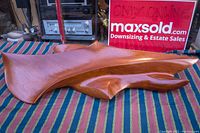 Top and angled side view of the solid teak wood abstract wall sculpture on striped fabric.