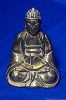 Front view of the brass sitting Buddha figurine on blue background