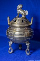 Photo of the incense burner showing overall profile, brass body with geometric pattern and Foo Dog finial on lid.