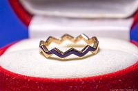 Rose gold plated zigzag ring displayed in a red and white ring box, showing the unique zigzag design.