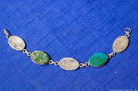 Full view of the oval linked bracelet on blue fabric background showing alternating oval silver and Eilat stone settings with clasp.