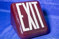 Front angled view of vintage glass EXIT light shade showing maroon color and white EXIT text