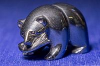 Close-up frontal image of the hematite black bear figurine showing its detailed carved features and the fish in its mouth.