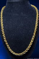 Full view of the gold plated necklace displayed on black stand showing length and chain style