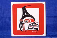 Front view of square ceramic tile showing Haida Indigenous bird design in black, red, and white with a thick red border. Signed Haida BK in bottom right.