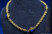 Full view of vintage Vendome gold plated necklace featuring decorative blue rhinestones on a rope chain design, shown on black display.