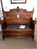 Full front view of walnut storage bench showing hinged upholstered seat and carved backrest