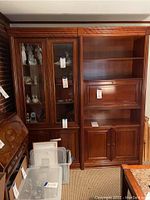 Full view of the cherry wood wall unit showing glass display cabinet on the left, open shelving and bar cabinet on the right.