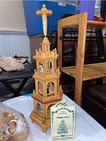 Full view of the 20-inch tall traditional German Christmas pyramid made of wood with multiple tiers and carved nativity figurines inside, placed on a white table.