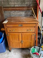 Front view of wooden kitchen island showing drawer, cabinet doors, and wheels.