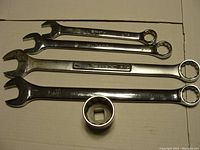 Overview of the 4 combination wrenches and 1 socket showing stamped sizes and brands on the tools.