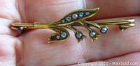 Front view showing the floral design with grey seed pearls on 14K yellow gold base, held in hand for scale.
