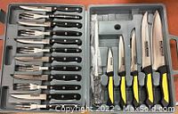 Overview of steak knives and forks with black handles arranged in the case.