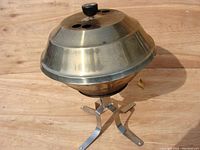 Full view of the stainless steel kettle grill with domed lid and metal stand on wooden surface.