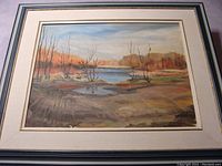 Framed oil painting showing the landscape scene including water and trees in fall tones.