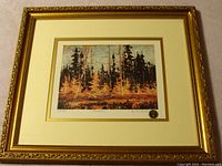 Framed print titled "Tamaracks" by Tom Thomson with colorful forest scene, visible numbering, and Group of 7 seal.