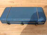 Closed blue metal case of Shepherd portable camping stove showing three control knobs.