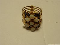 Front view of gold ring with clustered opal and sapphire stones, showing missing stones.