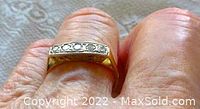 Top view of ring on a finger showing five round diamonds in a straight bar setting on yellow gold band.