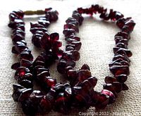 Close up of vintage garnet nugget necklace showing deep red glossy nuggets and clasp