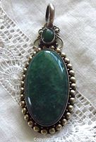 Front view of vintage jade and sterling silver pendant showing large oval and small oval jade stones with beaded silver frame