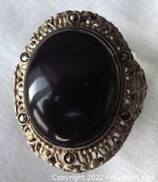 Top view of large oval black onyx cabochon surrounded by marcasite stones in filigree silver setting.