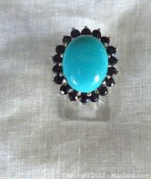 Front view showing large oval turquoise cabochon surrounded by dark blue sapphire-colored stones.