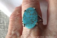 Top view of oval turquoise cabochon sterling ring on finger showing stone color and prong setting