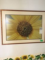 Framed sunflower print on wall showing close-up of sunflower center with yellow petals and brown seeds.