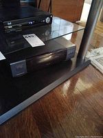 Front view of black Goldstar DVD player on shelf showing disc tray and side buttons.