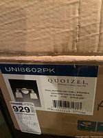 Label on the box showing brand Quoizel, model UNI8602PK, polished nickel finish, 21 watt bulb base, 15 inch width, 9 inch height, 6.25 inch depth.