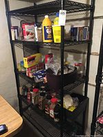 Full view of the assembled shelving rack loaded with kitchen pantry items. Five shelves visible with black metal wire design and black poles.